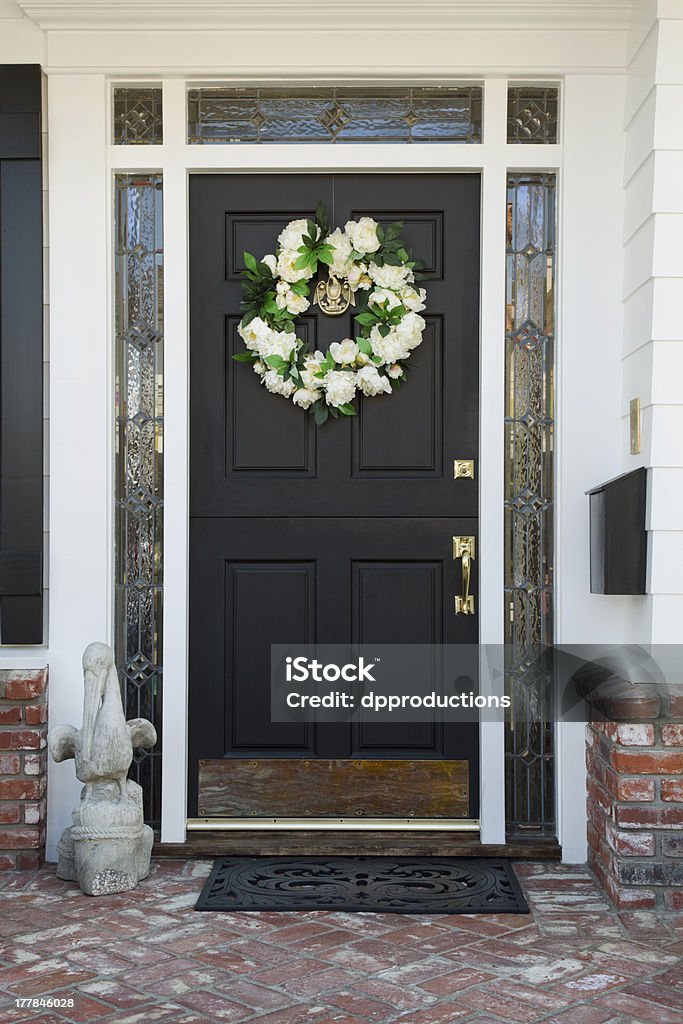 Front Door of a Home Exterior view of a front door to a residence with brick flooring and a wreath on the door. Vertical shot. Front Door Stock Photo