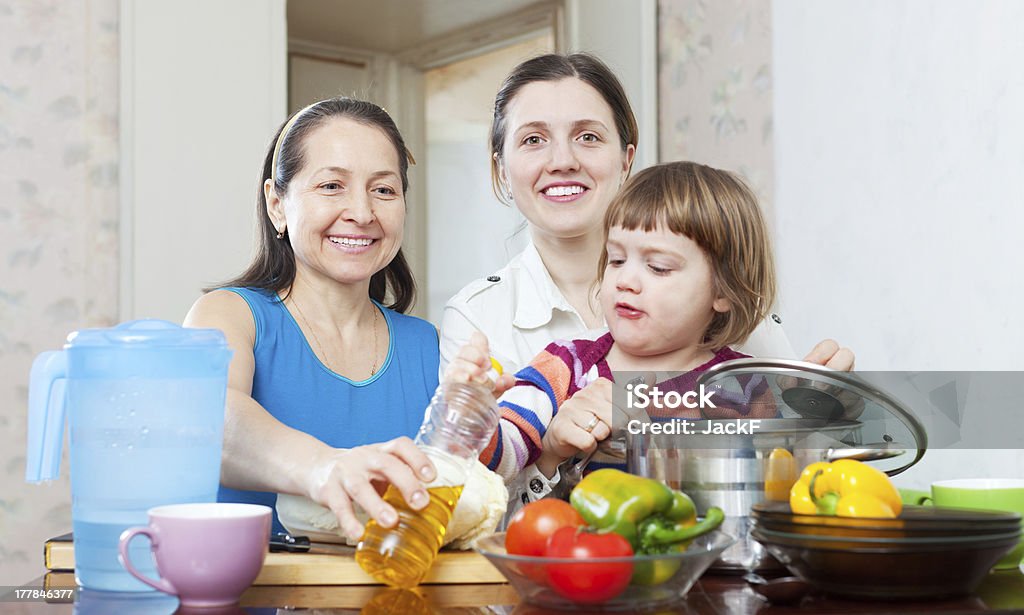 happy women with child  in kitchen happy women with child cook vegetables in kitchen 50-59 Years Stock Photo