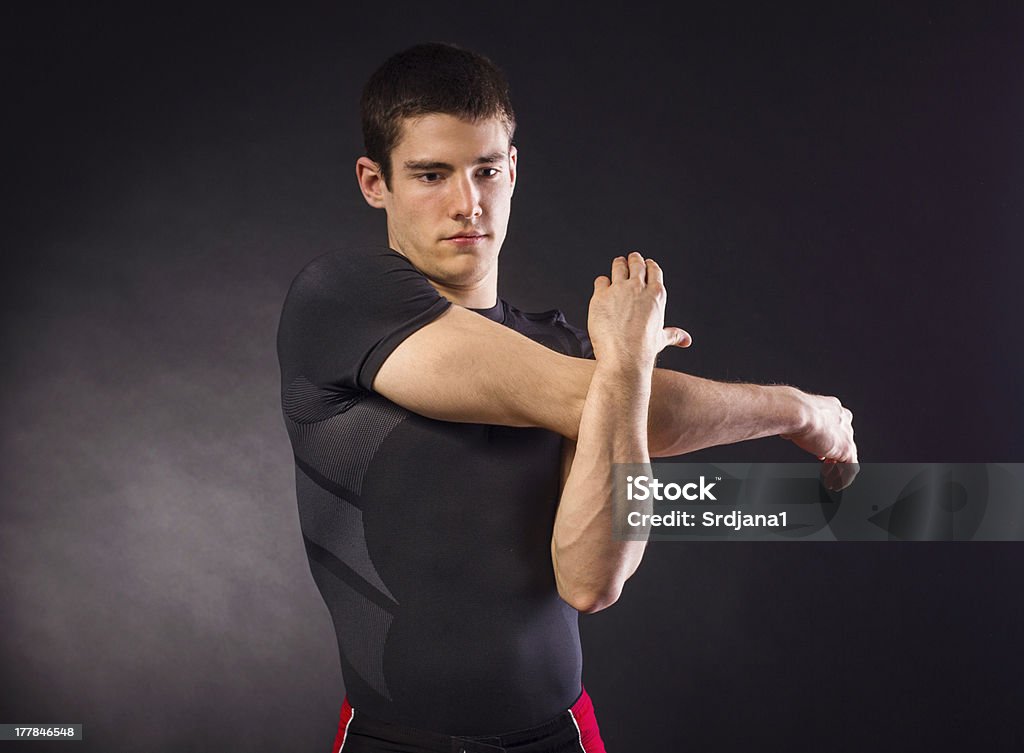 Muscoloso giovane uomo stretching - Foto stock royalty-free di Abbigliamento sportivo