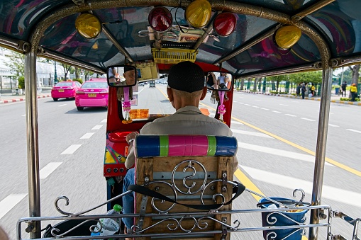 Bangkok, Thailand - 14 October 2022: Rear view of Tuk Tuk driver. Popular way to travel around bangkok.