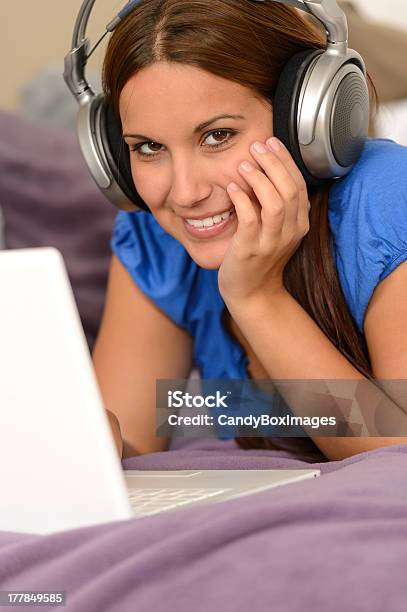 Chica Joven Sonriente Con Ordenador Portátil Y Auriculares Integrados Foto de stock y más banco de imágenes de Acostado