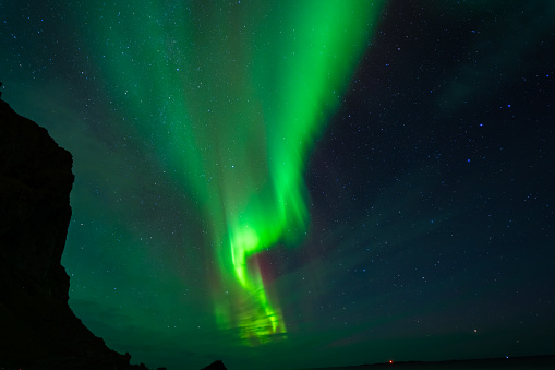 Northern lights over the beach, reflection in the silky water. Lofoten islands, Norway.