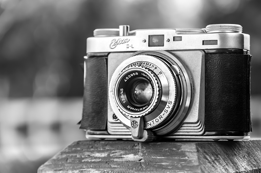 The photo shows an Edixa brand II-L 35 film camera worn by years of use having taken thousands of photographs.   This particular model was produced around 1957.  The grainy black and white image and worn features purposely evoke a sense of the passage of time.   These types of photos represent the unique timeless nature of monochrome photography.