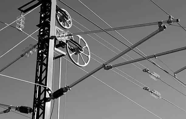 Electrical system of energy transmission to railroad black and white isolated on grey sky