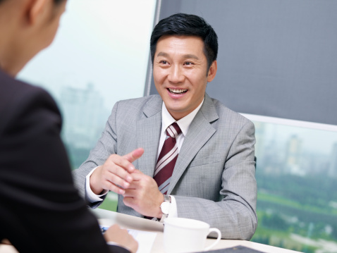 asian businessman discussing business with colleague in office, looking excited. click for more: