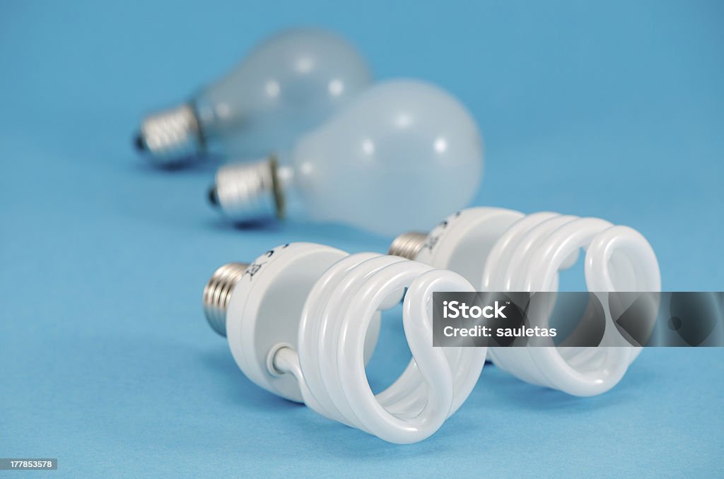 two pair of light bulbs  new fluorescent heat bulb two pair of new and old bulbs. novel modern fluorescent lights and old incandescent heat bulb on blue background. economic technology for less electricity energy consumption. Blue Stock Photo