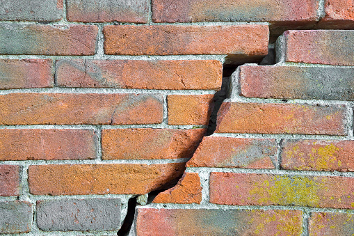 Dangerous old exposed cracked brick wall due to structural foundation failure, soil subsidence, corrosion and deterioration of building materials, earthquake