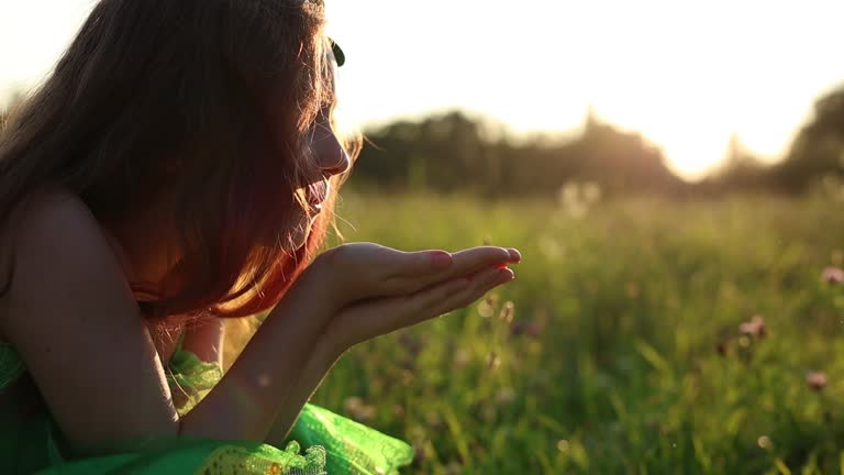 Little leprechaun girl blowing glitter sparkles in slow motion. Red head child in a fairy dress celebrates St Patricks Day