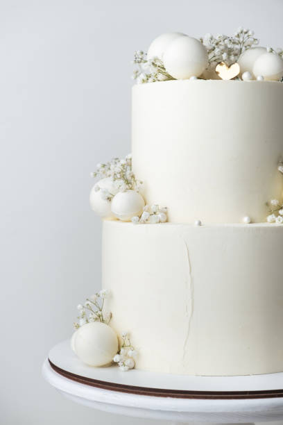 istock Big bunk wedding cake covered with white chocolate frosting and decorated with white chocolate spheres on the white background. 1778552962