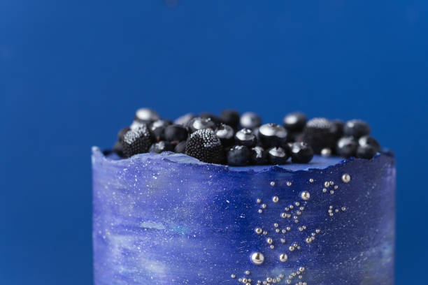 istock Birthday cake with blue cream cheese frosting decorated with blueberries covered with silver kandurin. Cosmic cake or space themed cake on blue background. 1778552973