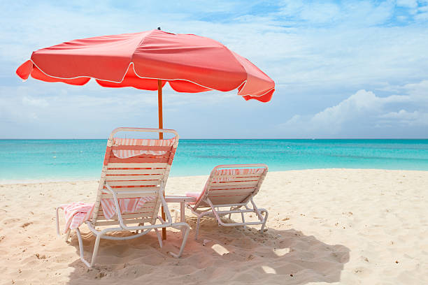 Tropical beach Pink umbrella and chairs on a beautiful Caribbean beach providenciales stock pictures, royalty-free photos & images