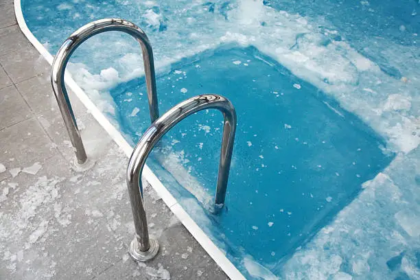Photo of Ice swimming theme. Steps in the frozen blue pool ice-hole