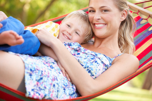 Mother And Son Relaxing In Hammock Hugging Each Other Smiling