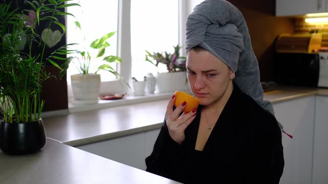Sick woman trying to sense smell of fresh orange
