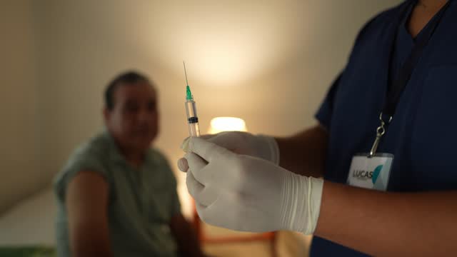 Male nurse giving injection to a senior man patient at his house