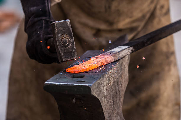 Close-up photo of a hammer striking a heated piece of metal stock photo
