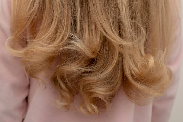 uma garota está de pé para trás com lindos cabelos encaracolados - fashion shiny blond hair ringlet - fotografias e filmes do acervo