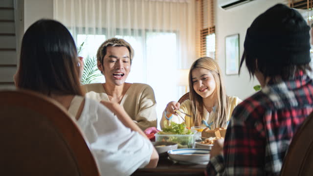 Group of young millennial Asian teenager enjoy party meal at home, brunch or lunch table, close friend fun and laugh happy together. Diverse gender with LGBTQ+ people. Social meeting concept