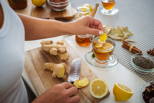 kobieta przygotowująca gorącą herbatę z imbirem i cytryną - ginger tea cup cold and flu tea zdjęcia i obrazy z banku zdjęć