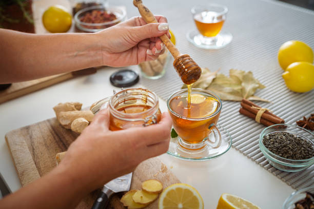 istock Woman adding honey to a ginger and lemon tea cup 1778620978
