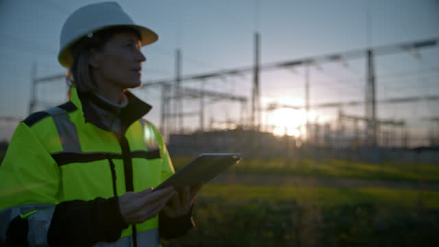 SLO MO Electrical Engineer Walking At Power Station And Using Digital Tablet Suring Sunset
