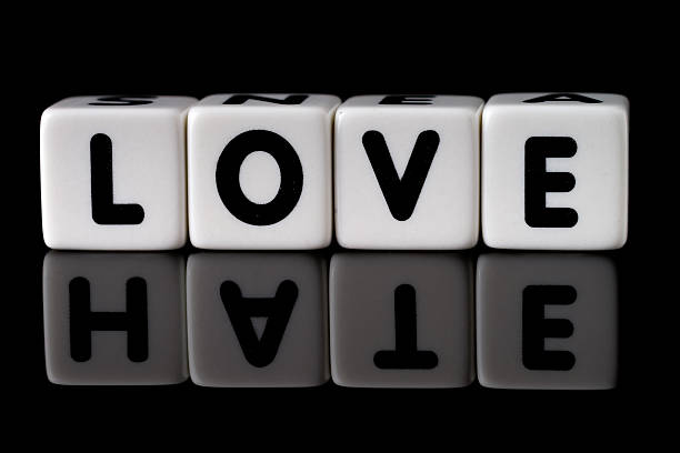 Love Hate Concept Love spelled in dice with the word hate reflected on black isolated background furious stock pictures, royalty-free photos & images