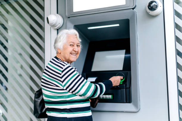 istock Old woman picking money using ATM 1778640340