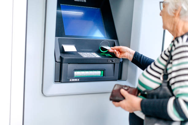 istock Old woman using credit card in front of ATM 1778640343