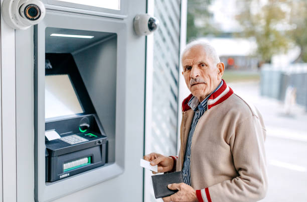 istock Old man picking money using credit card in front of ATM 1778640349