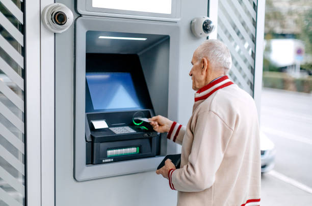 istock Old man picking money using credit card in front of ATM 1778640351
