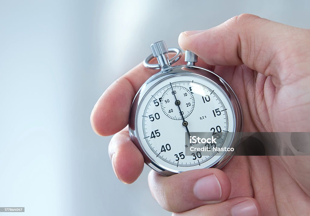 A man holding a stopwatch on his hand Analog stopwatch in human hand, toned blue Stopwatch Stock Photo