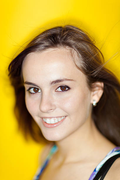 Atractiva Mujer sonriendo a la cámara con fondo amarillo - foto de stock