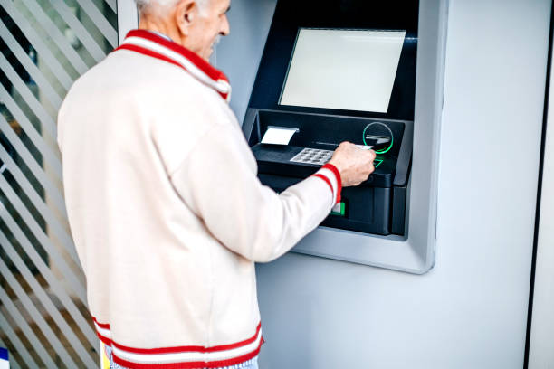 istock Old man picking money using credit card in front of ATM 1778640580