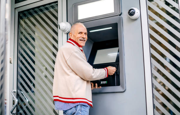 istock Old man picking money using credit card in front of ATM 1778640861