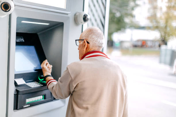 istock Old man picking money using smart watch in front of ATM 1778640881