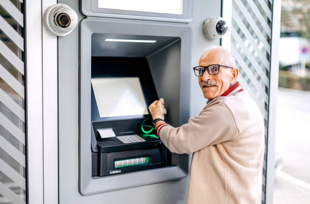 istock Old man picking money using smart watch in front of ATM 1778640884