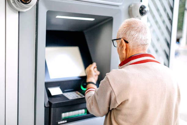 istock Old man picking money using smart watch in front of ATM 1778641393