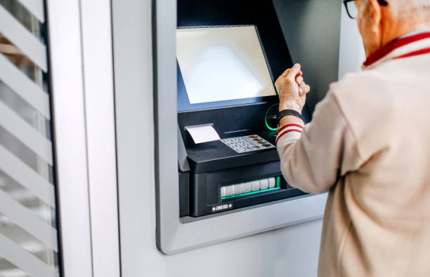 istock Old man picking money using smart watch in front of ATM 1778641413