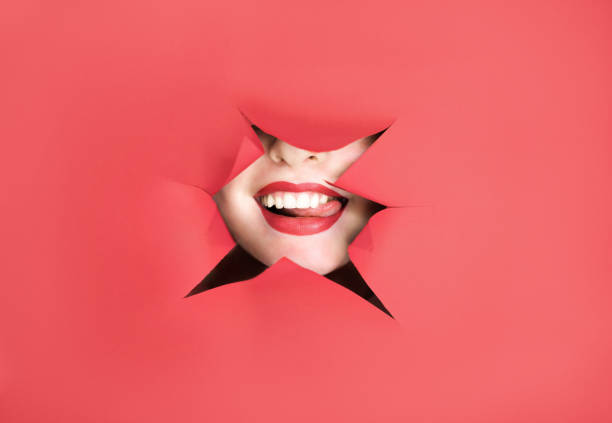 istock Makeup Concept. Woman Playing With Tongue Through Hole In Torn Red Paper 1778642014