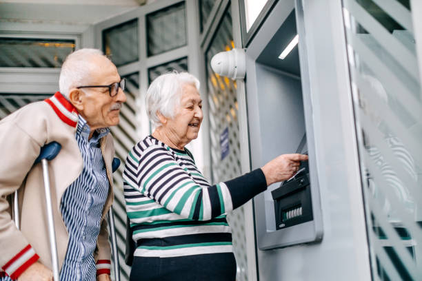 istock Old couple picking money using credit card in front of ATM 1778643779