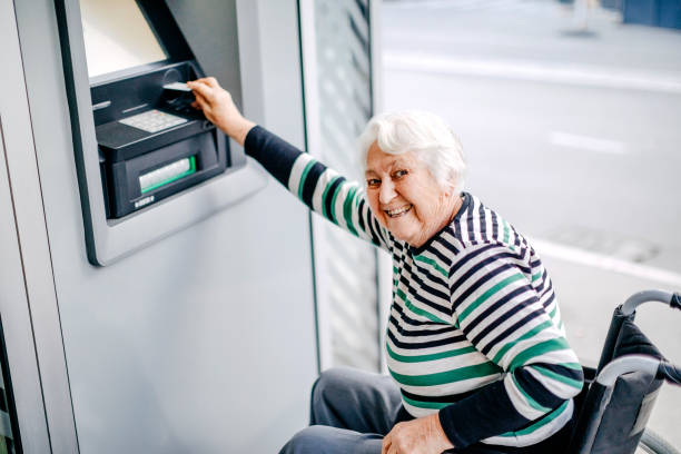 istock Old woman in wheelchair picking money using ATM 1778646093