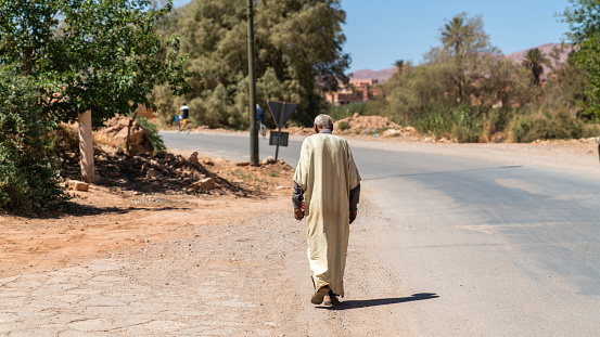Morocco - 17 September 2022: Old man in traditional clothing walking through the rural landscape of Morocco