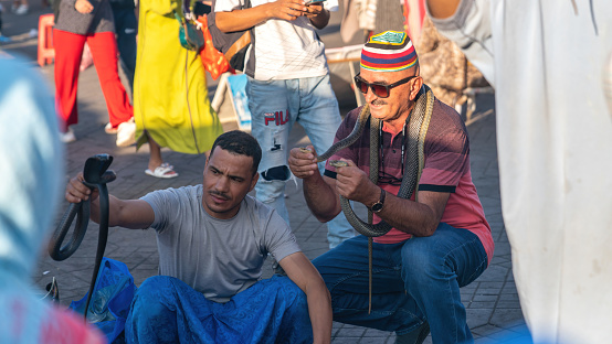 Marrakesh, Morocco - 15 September 2022: Snake charmer in Jemaa el Fnaa city square in the old city of Marrakesh. The square is full of many tourist activities.