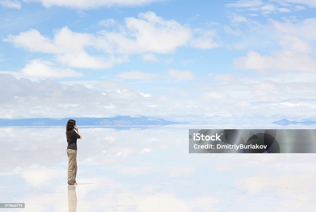Girl talking on the phone Girl talking on the mobile phone in the middle of the lake Salar de Uyuni Adult Stock Photo