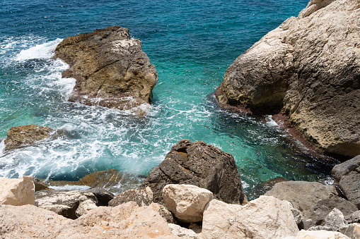 foaming turquoise clear sea water flowing over the rocks, Mediterranean seascape with beige cliffs