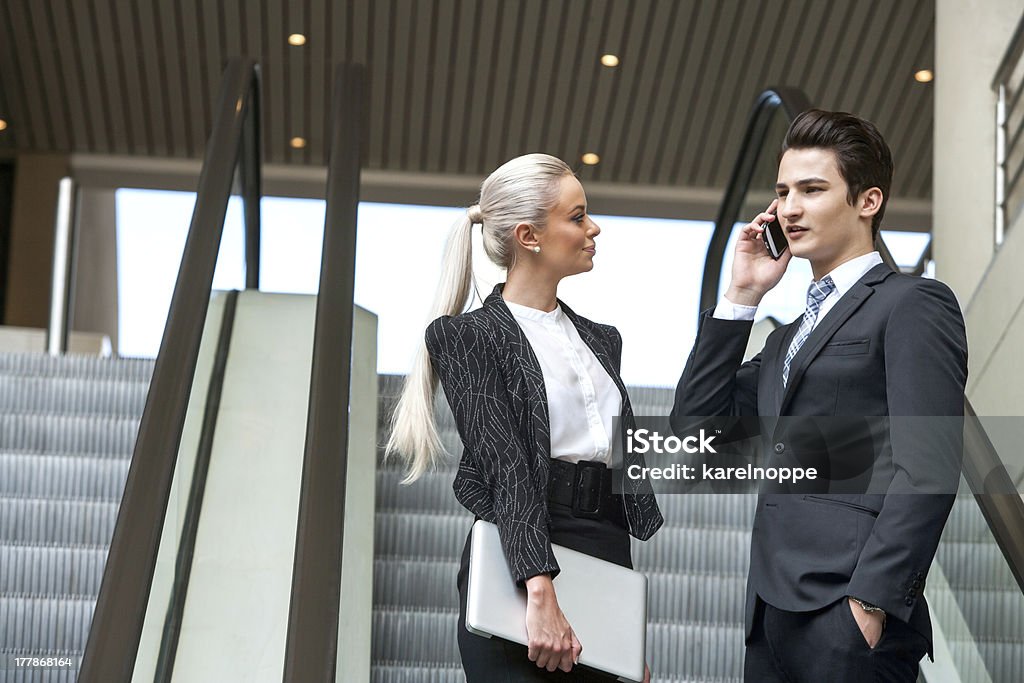Business colleagues on escalator. Young Business partners having conversation on escalator in mall. Adult Stock Photo