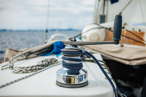 Winch with rope and handle on sailing boat during sailing.