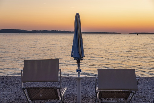 Picture of the sunset on the beach of the Croatian coastal town of Fazana with sun lounger and parasol in summer