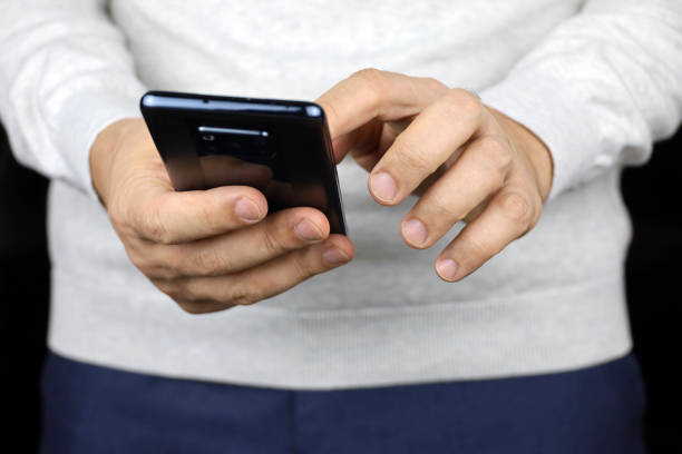 istock Man in white sweater holding smartphone in hands 1778703796