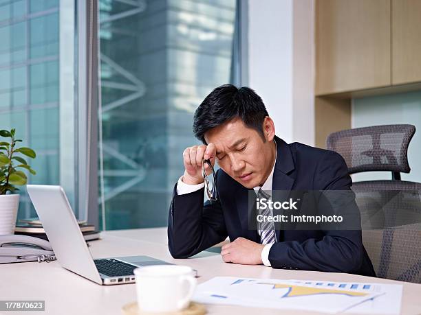 Stressed Businessman Rubbing Head Looking At Charts Stock Photo - Download Image Now